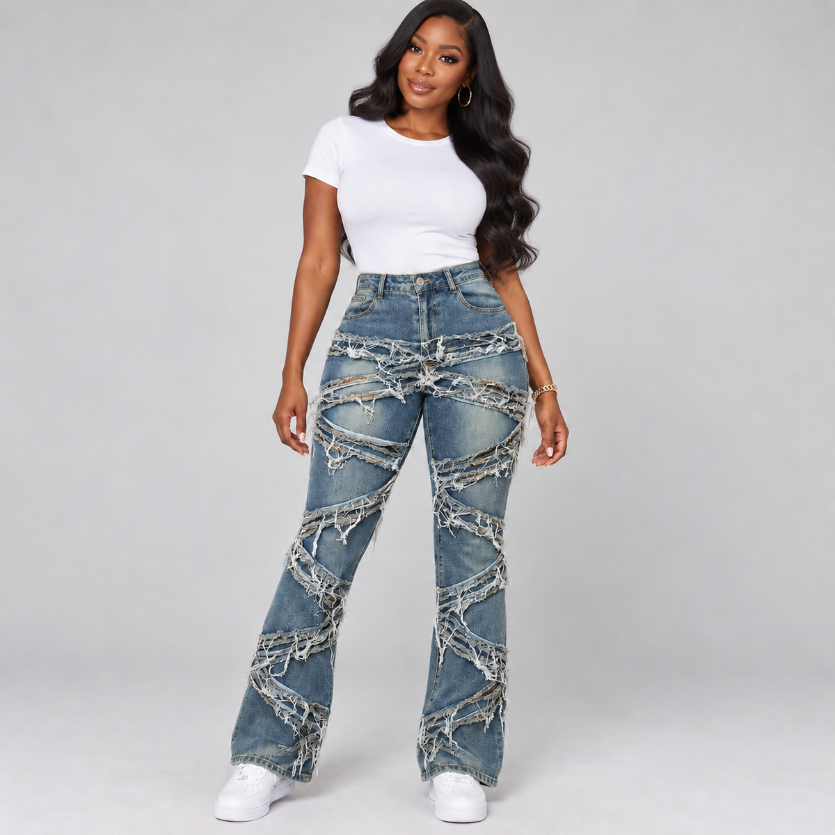 Black model with body-wave hair and hoop earrings wearing distressed blue jeans, a white shirt and white sneakers